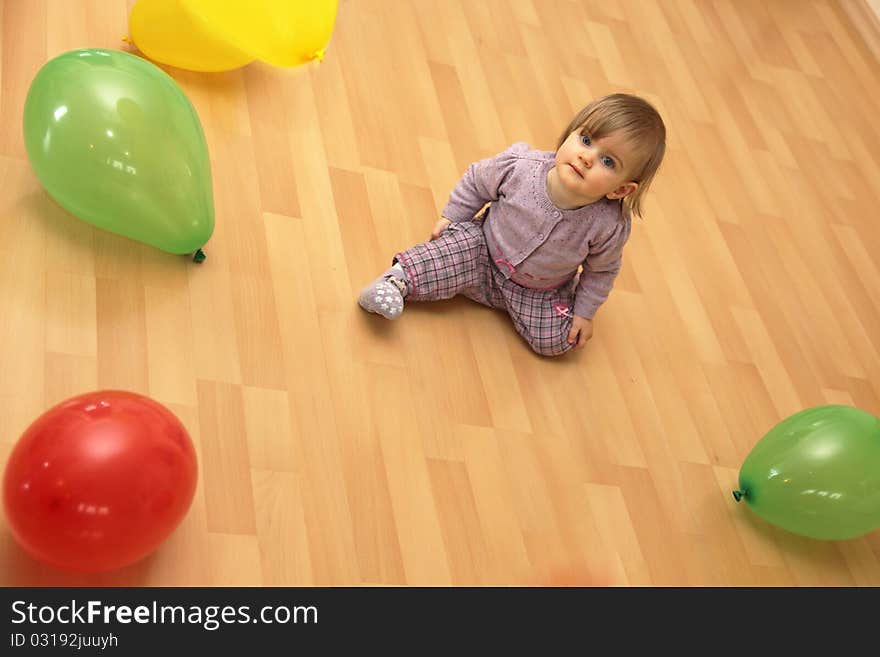 Small child sits in the middle of many colorful balloons, Copy Space