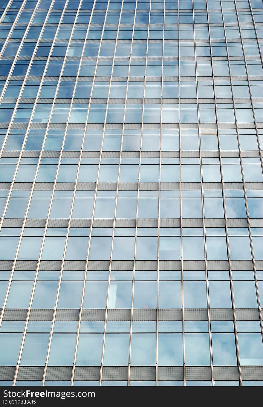 Modern building reflecting blue sky and clouds in the office windows.