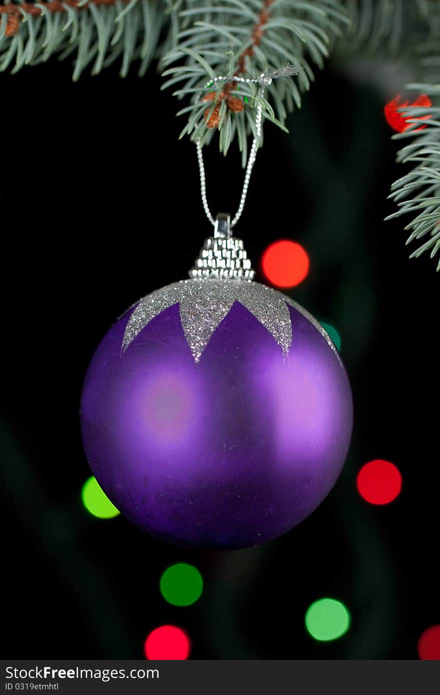 Violet christmas ball with a christmas tree on the black background