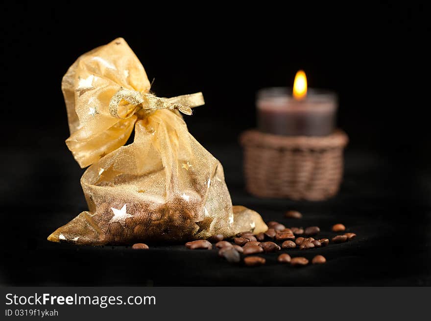 Golden christmas sack with the coffee beans and burning candle. Golden christmas sack with the coffee beans and burning candle