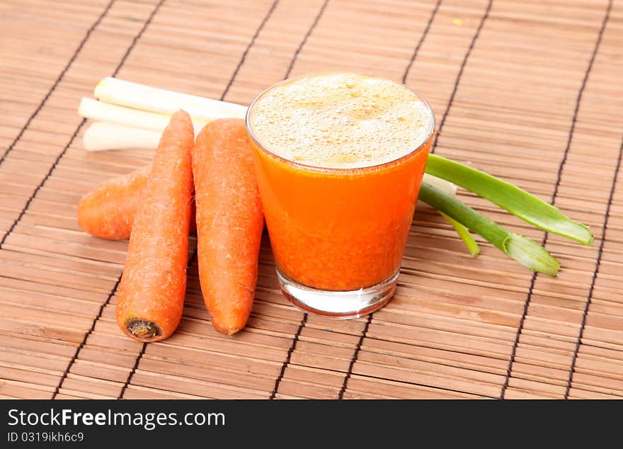 Carrot juice with vegetables over bamboo background