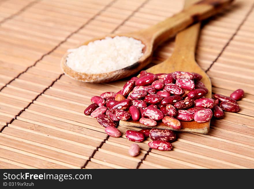 Wooden spoons with beans and rice oil over bamboo background. Wooden spoons with beans and rice oil over bamboo background