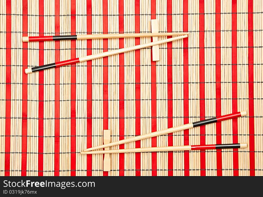 Red and black sticks for sushi on bamboo mat