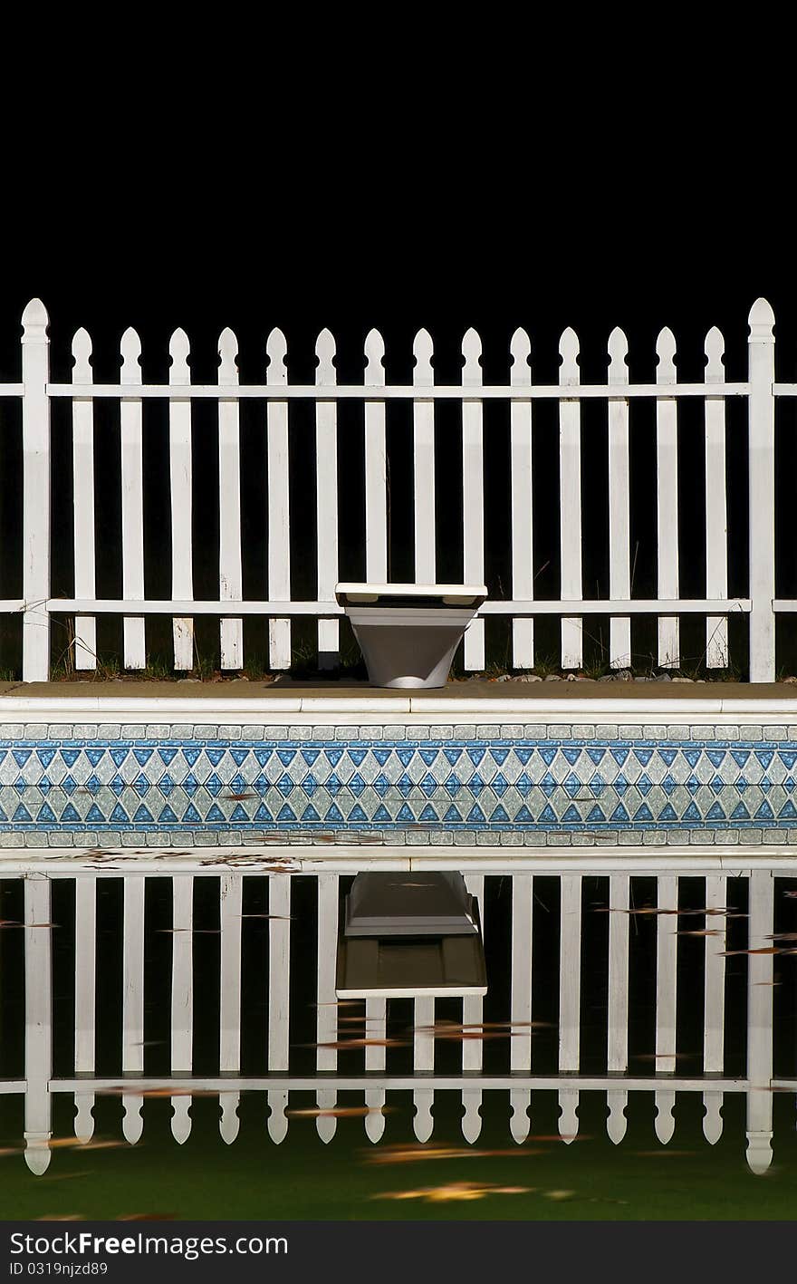 A Swimming Pool and White Picket Fence at Night. A Swimming Pool and White Picket Fence at Night