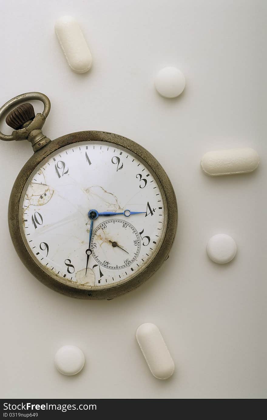 Old pocket watch surrounded by pills. Old pocket watch surrounded by pills