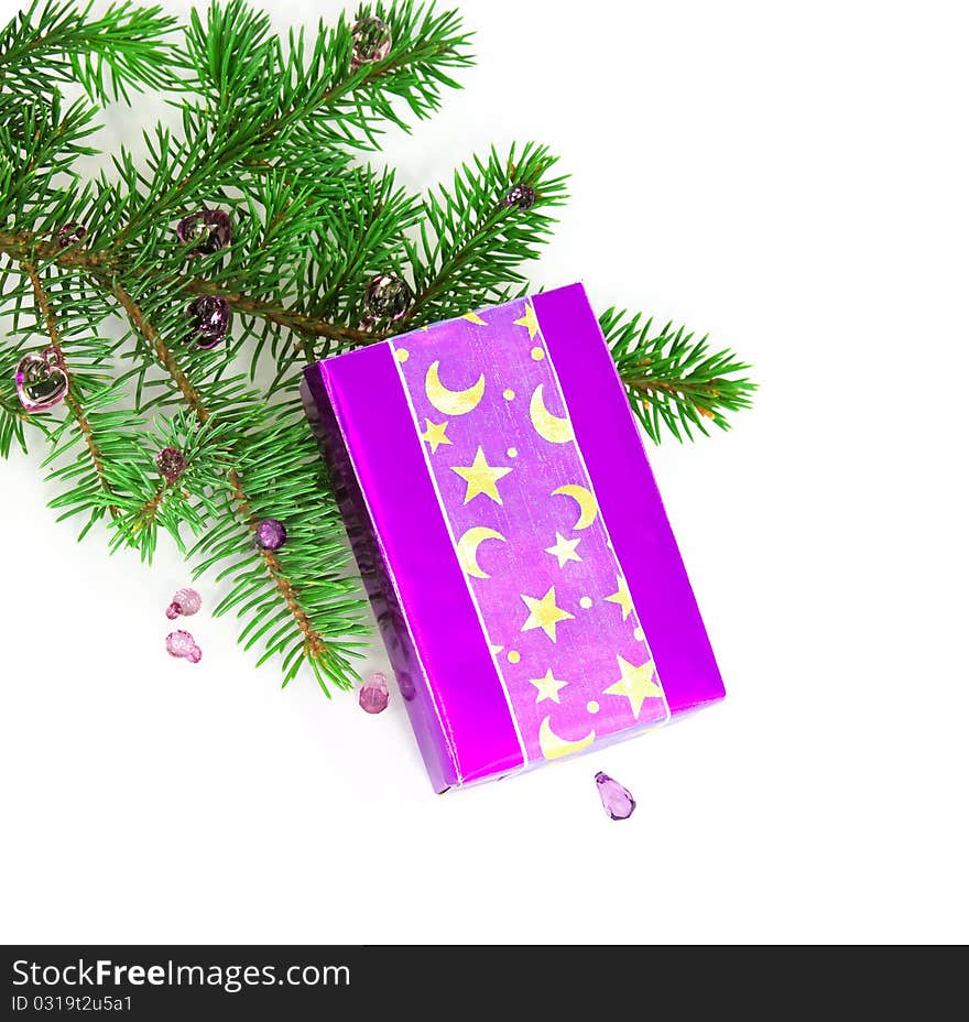 Lilac gift box against a New Year tree branch, white background. Lilac gift box against a New Year tree branch, white background