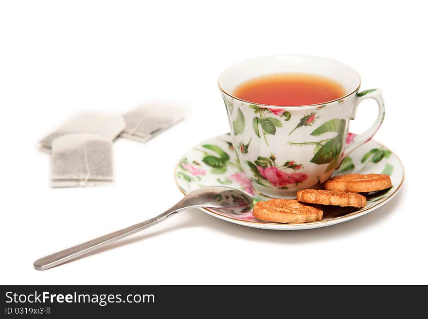 Colored cup of black tea, cookies and tea bags on white at 15Mps. Colored cup of black tea, cookies and tea bags on white at 15Mps