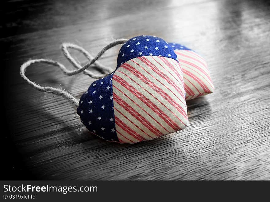 Selective color was used on two fabric hearts that are resting on an oak table. Selective color was used on two fabric hearts that are resting on an oak table.