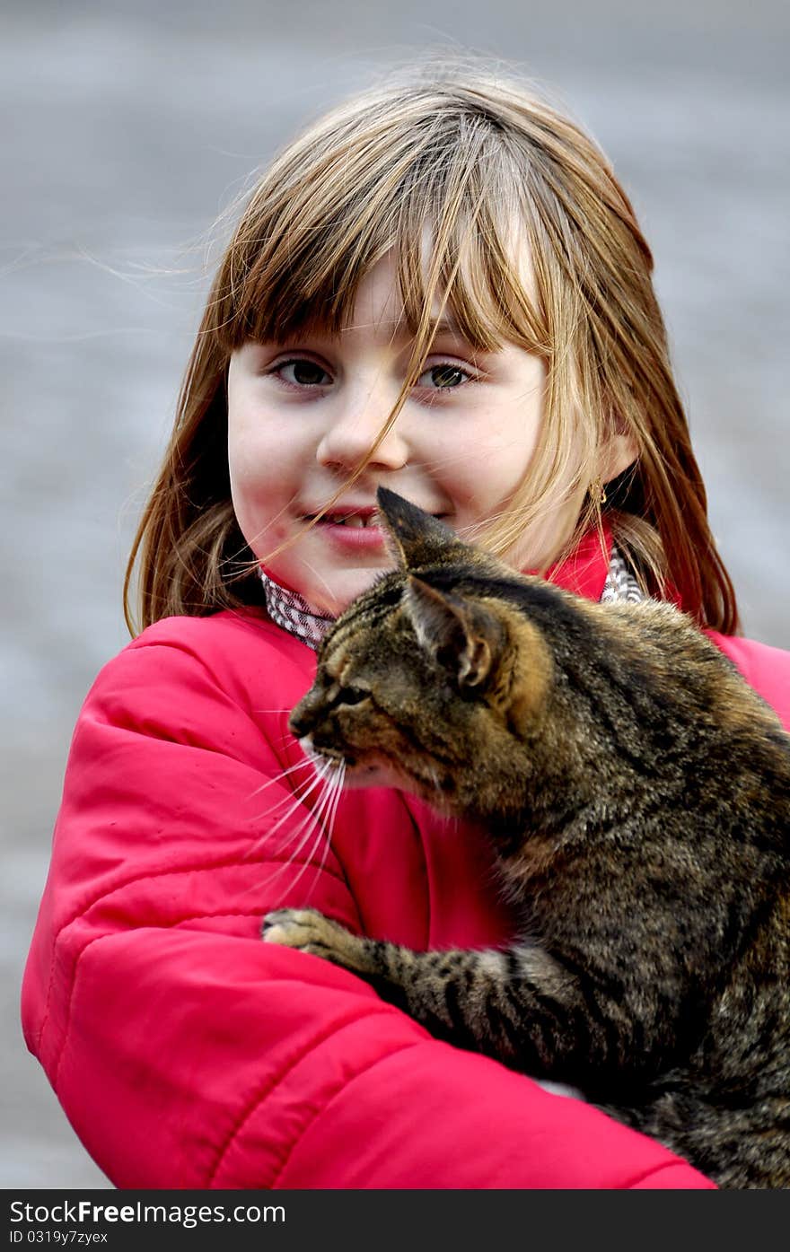 A pretty young blonde girl holds a calico cat. A pretty young blonde girl holds a calico cat.