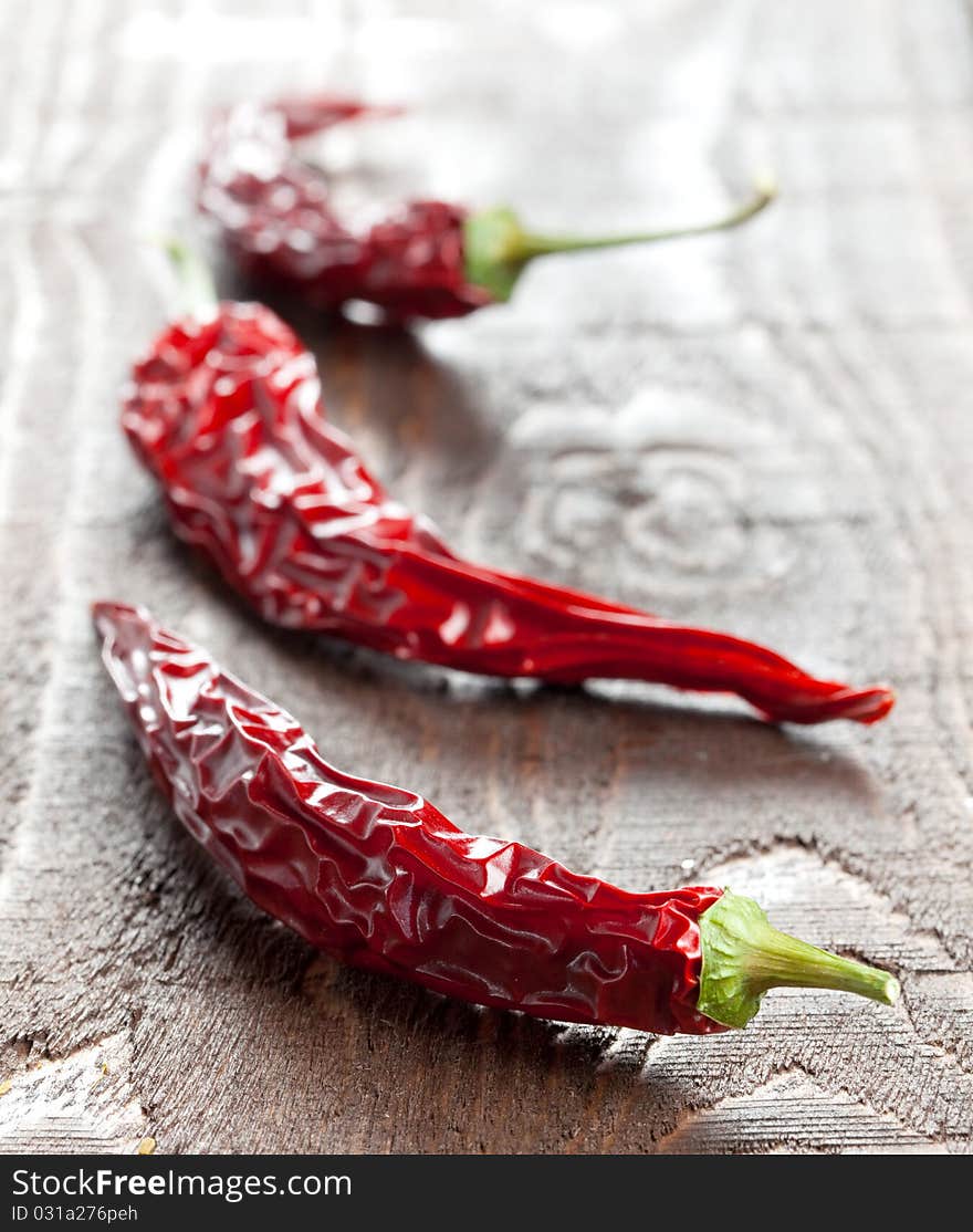 Three dried chili pepper on wooden table