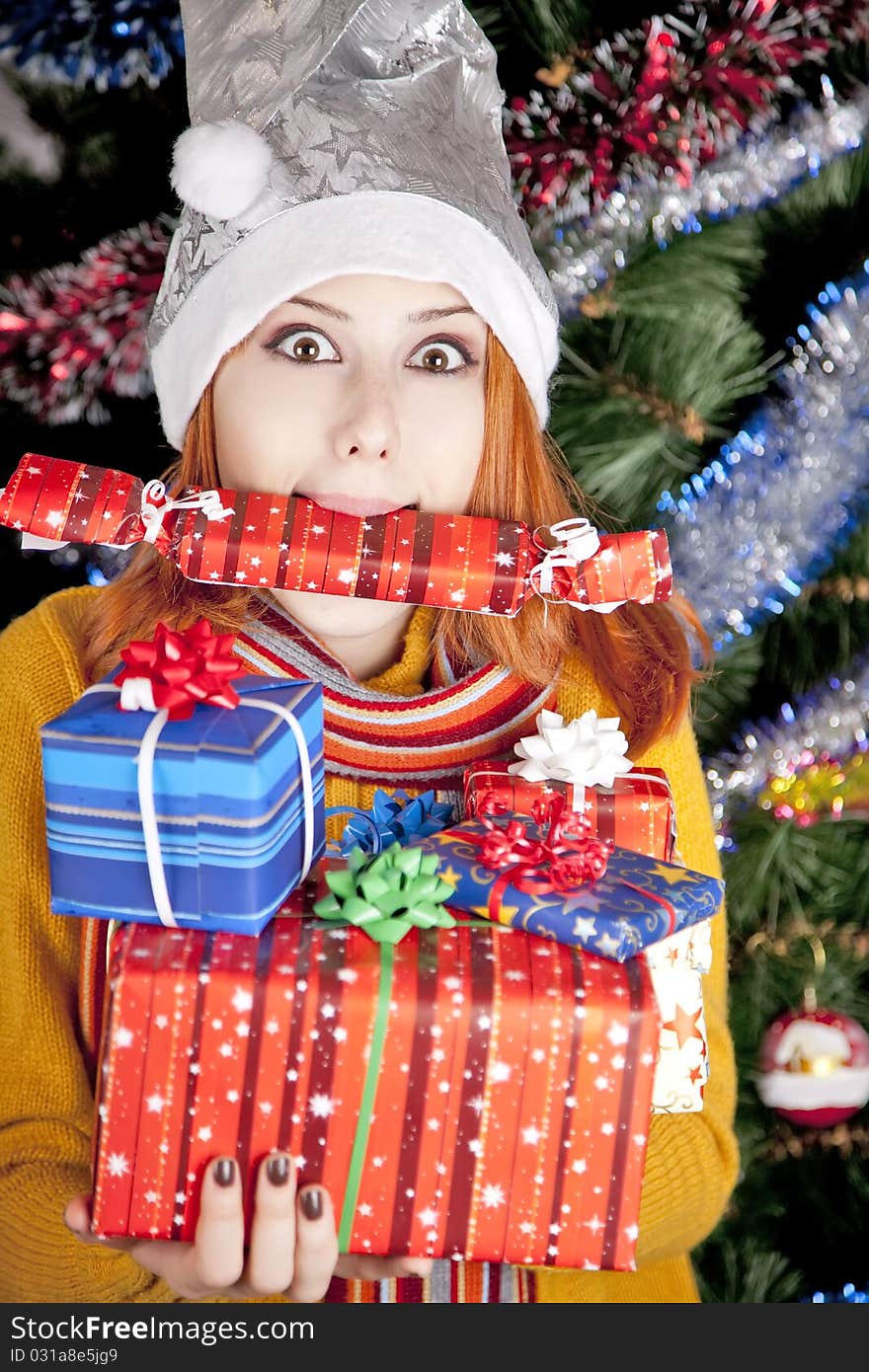 Funny girl in christmas cap with gift boxes