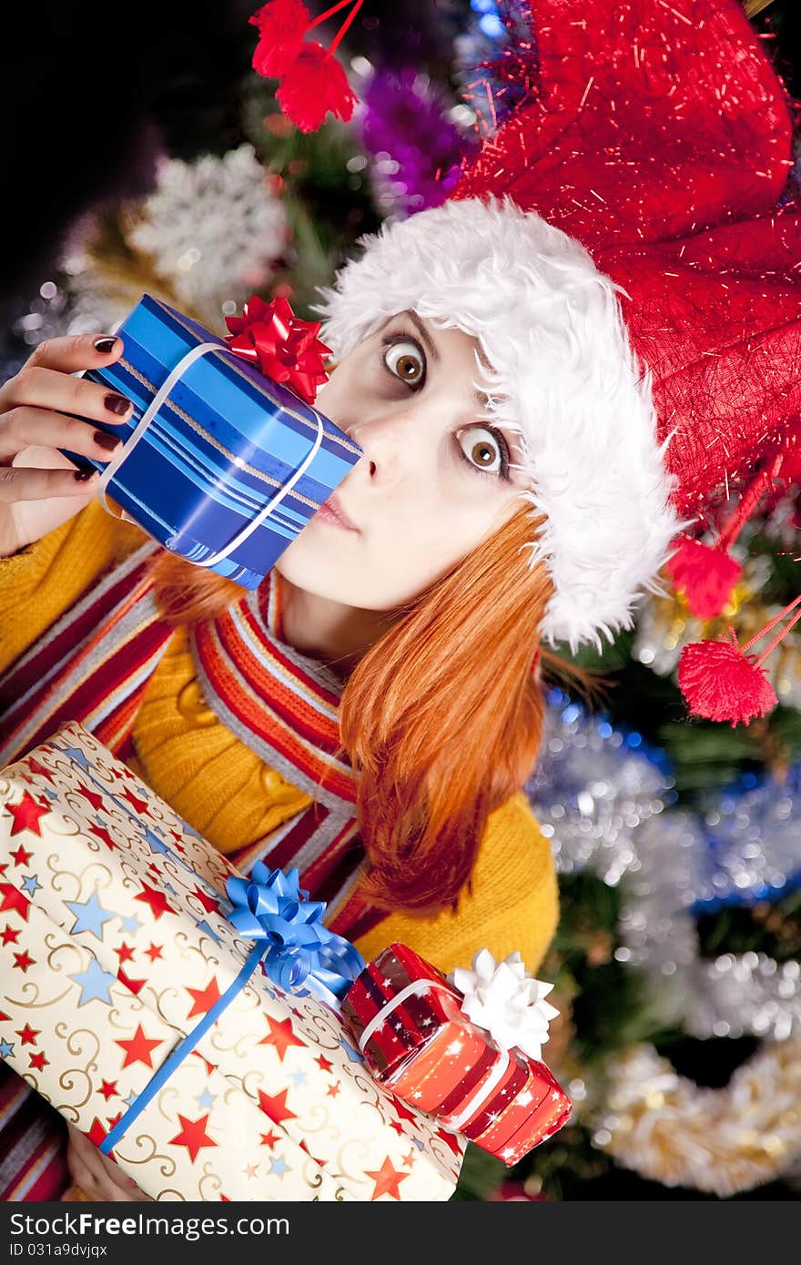 Funny girl in christmas cap with gift boxes