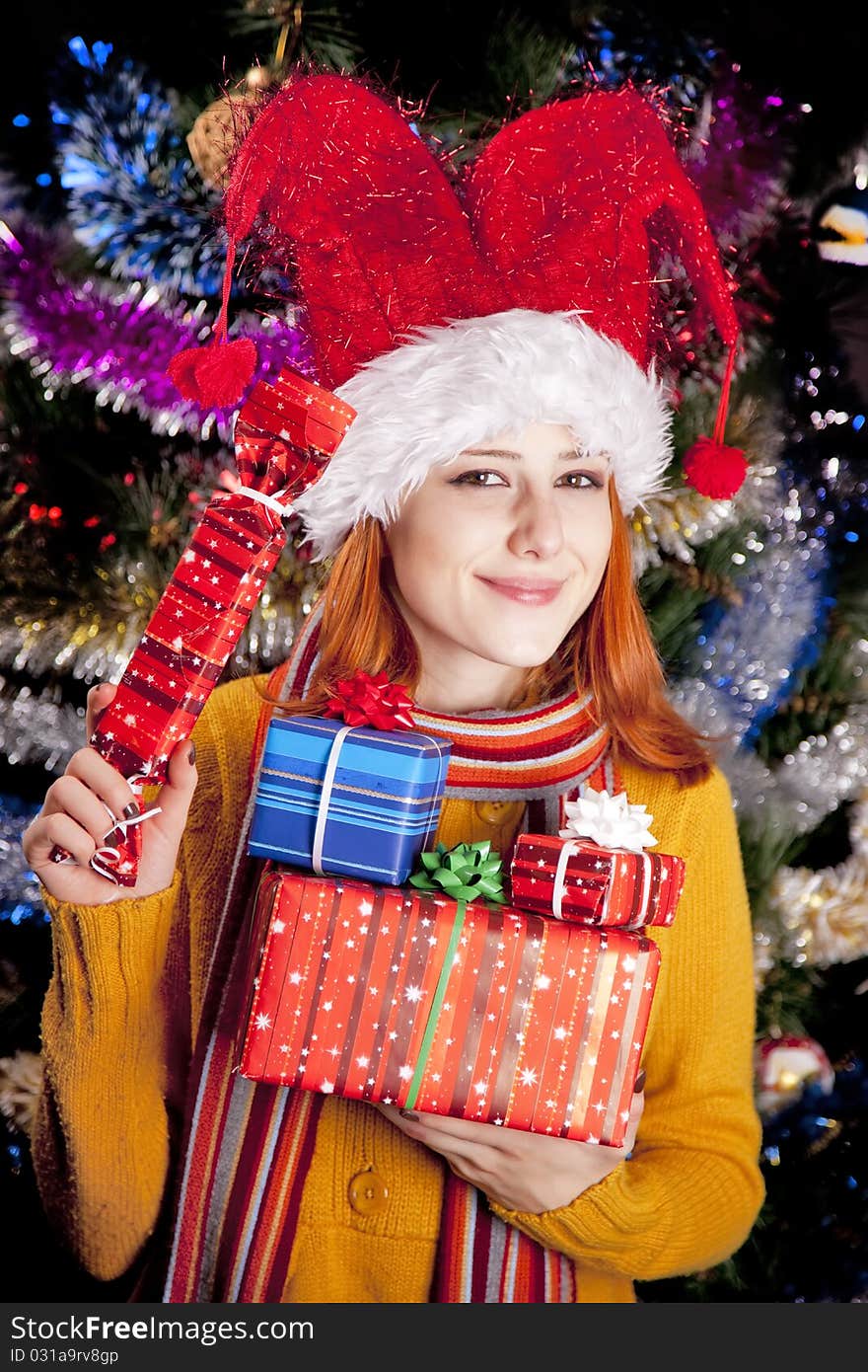 Funny girl in christmas cap with gift boxes