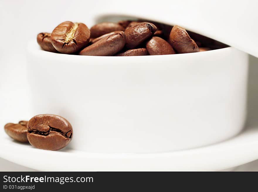 Coffee beans in a white porcelain cup. Coffee beans in a white porcelain cup.