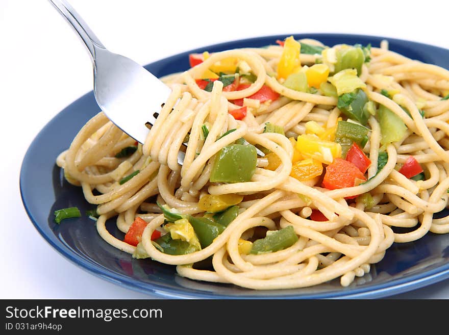 Spaghetti with vegetables being eaten with a fork on white background