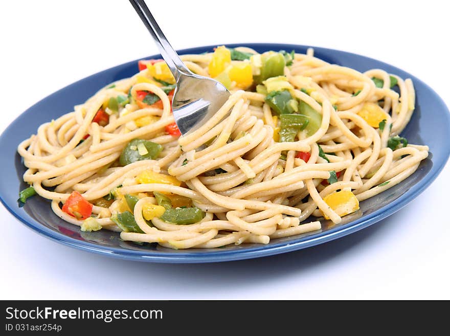 Spaghetti with vegetables being eaten with a fork on white background