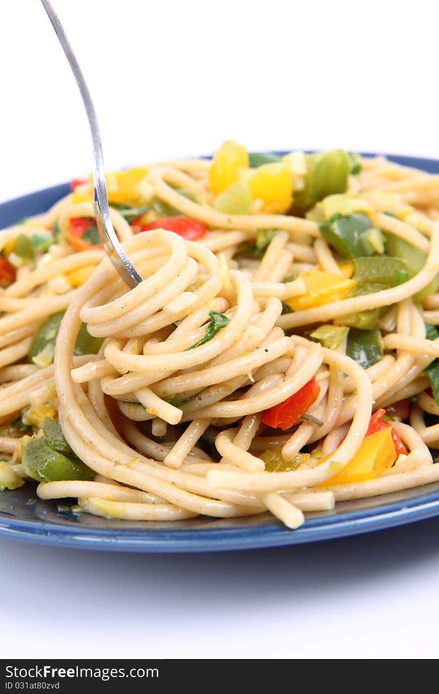 Spaghetti with vegetables being eaten with a fork on white background