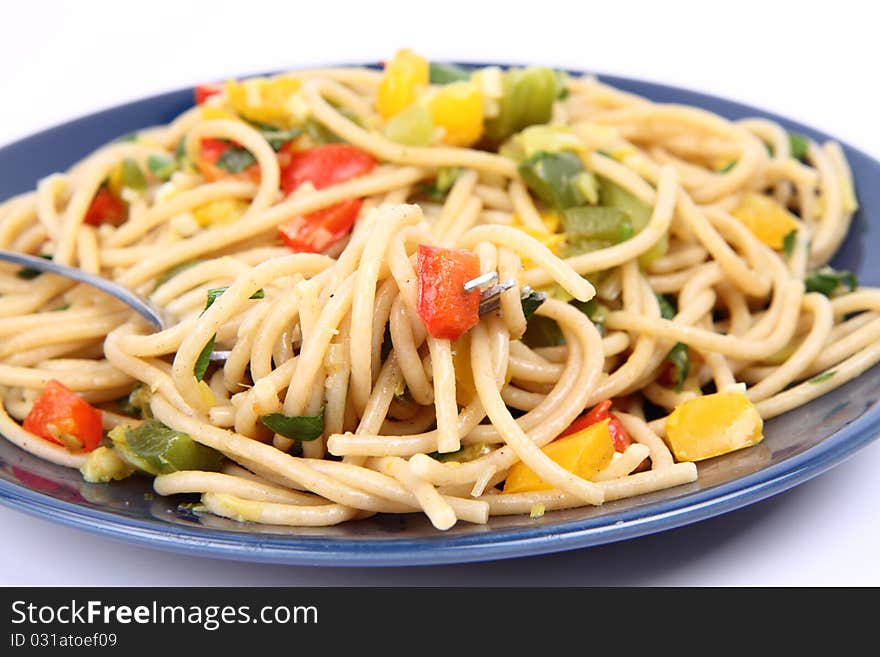 Spaghetti with vegetables with a fork on white background