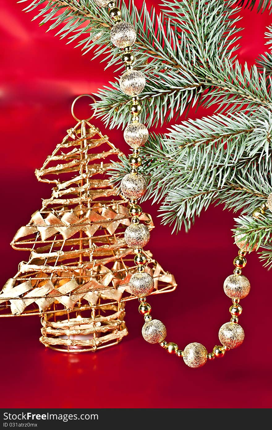 On a red background with a spruce twig Christmas decoration ball on a string of candlesticks. On a red background with a spruce twig Christmas decoration ball on a string of candlesticks.