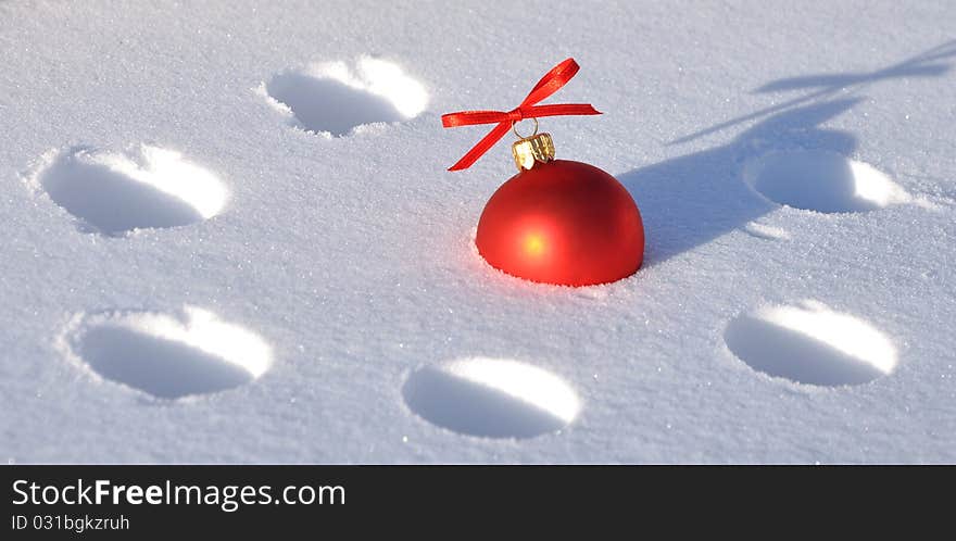 A red Christmas bauble sitting in a bed of snow. A red Christmas bauble sitting in a bed of snow