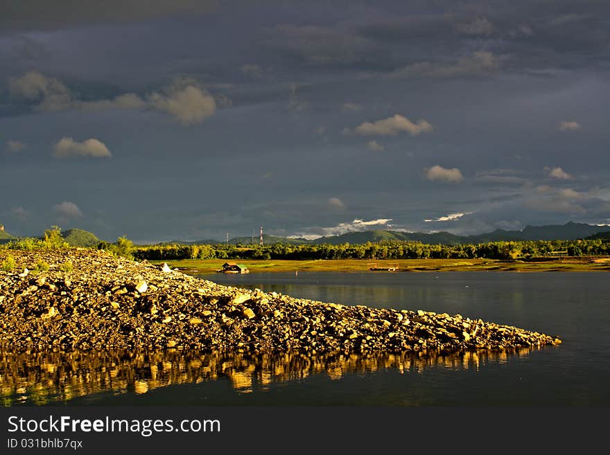 Mound on lakeside and dark sky after rain in Kanchanaburi ,Thailand