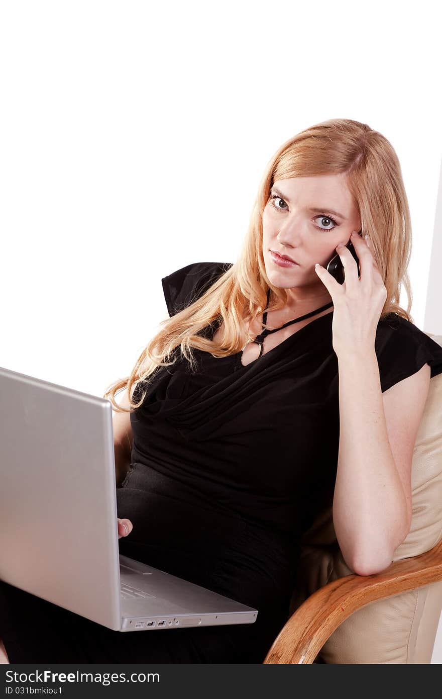 A business woman listening to a call on her cell while she is working on her laptop. A business woman listening to a call on her cell while she is working on her laptop.