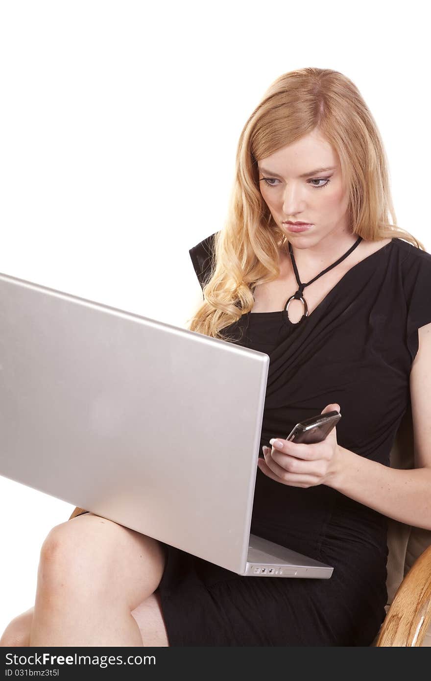 A woman getting a text on her cell phone while she is working on her laptop. A woman getting a text on her cell phone while she is working on her laptop.