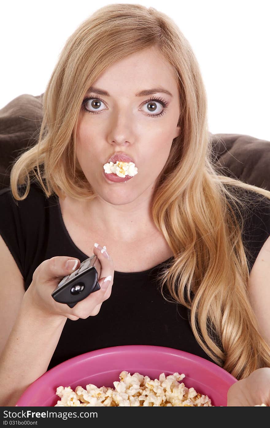 A woman sitting on a bean bag while she is enjoying her popcorn with it falling out of her mouth. A woman sitting on a bean bag while she is enjoying her popcorn with it falling out of her mouth.