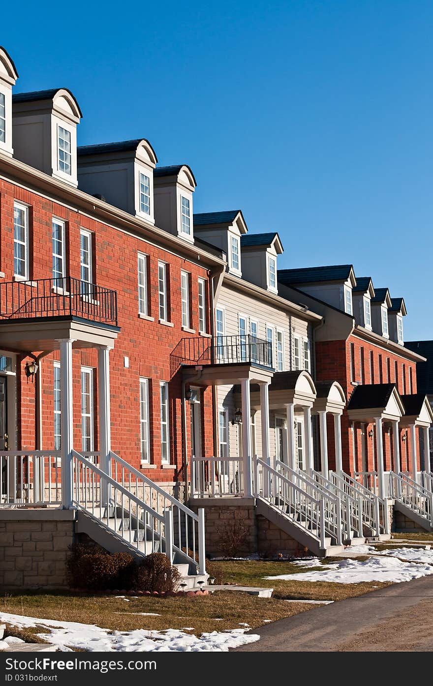 A row of recently built townhouses on a suburban street in winter.