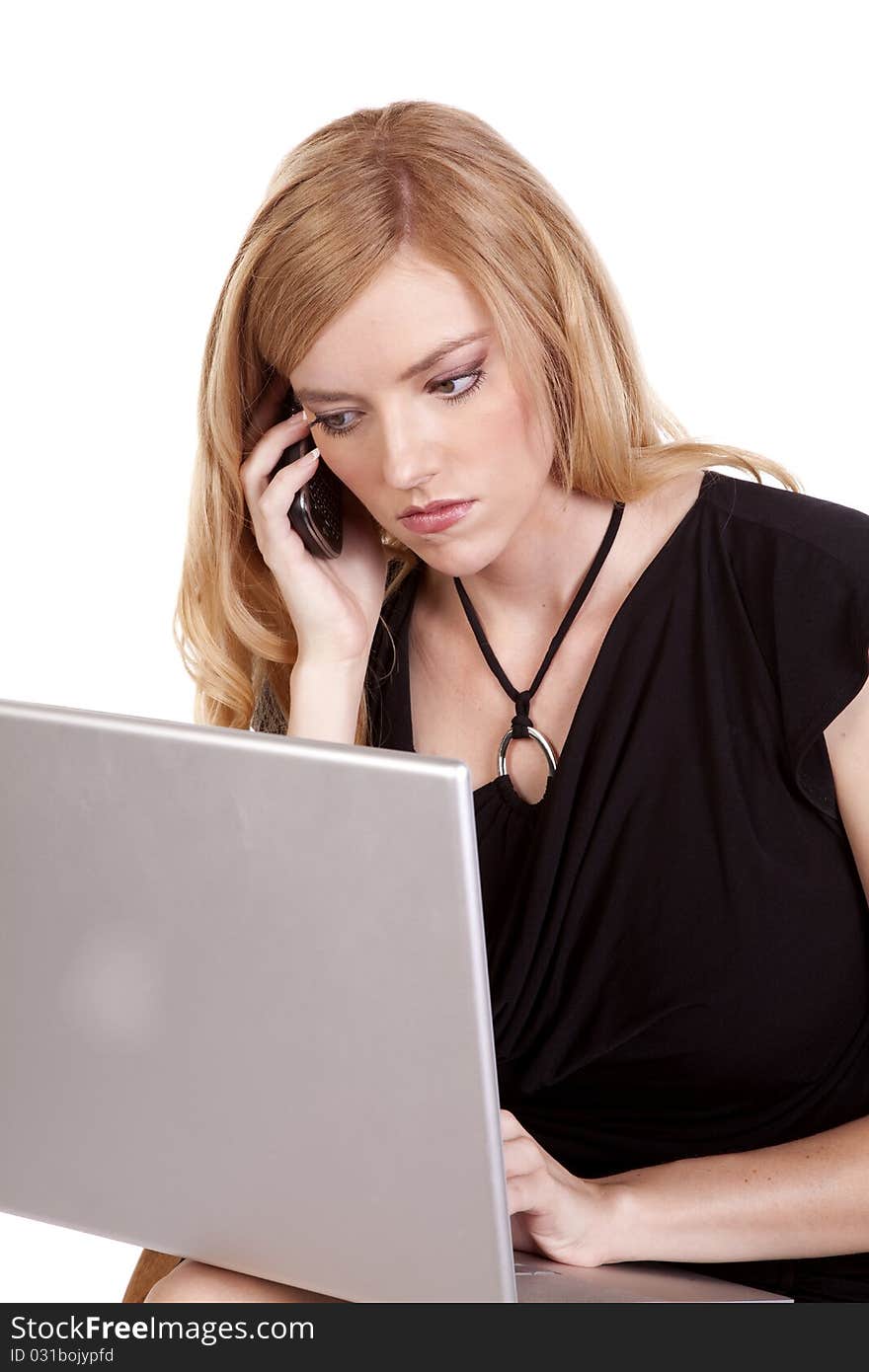 A business woman listening to a call on her cell while she is working on her laptop. A business woman listening to a call on her cell while she is working on her laptop.