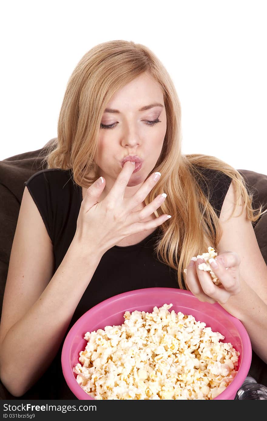 A woman sitting on a bean bag while she is enjoying her popcorn. A woman sitting on a bean bag while she is enjoying her popcorn.