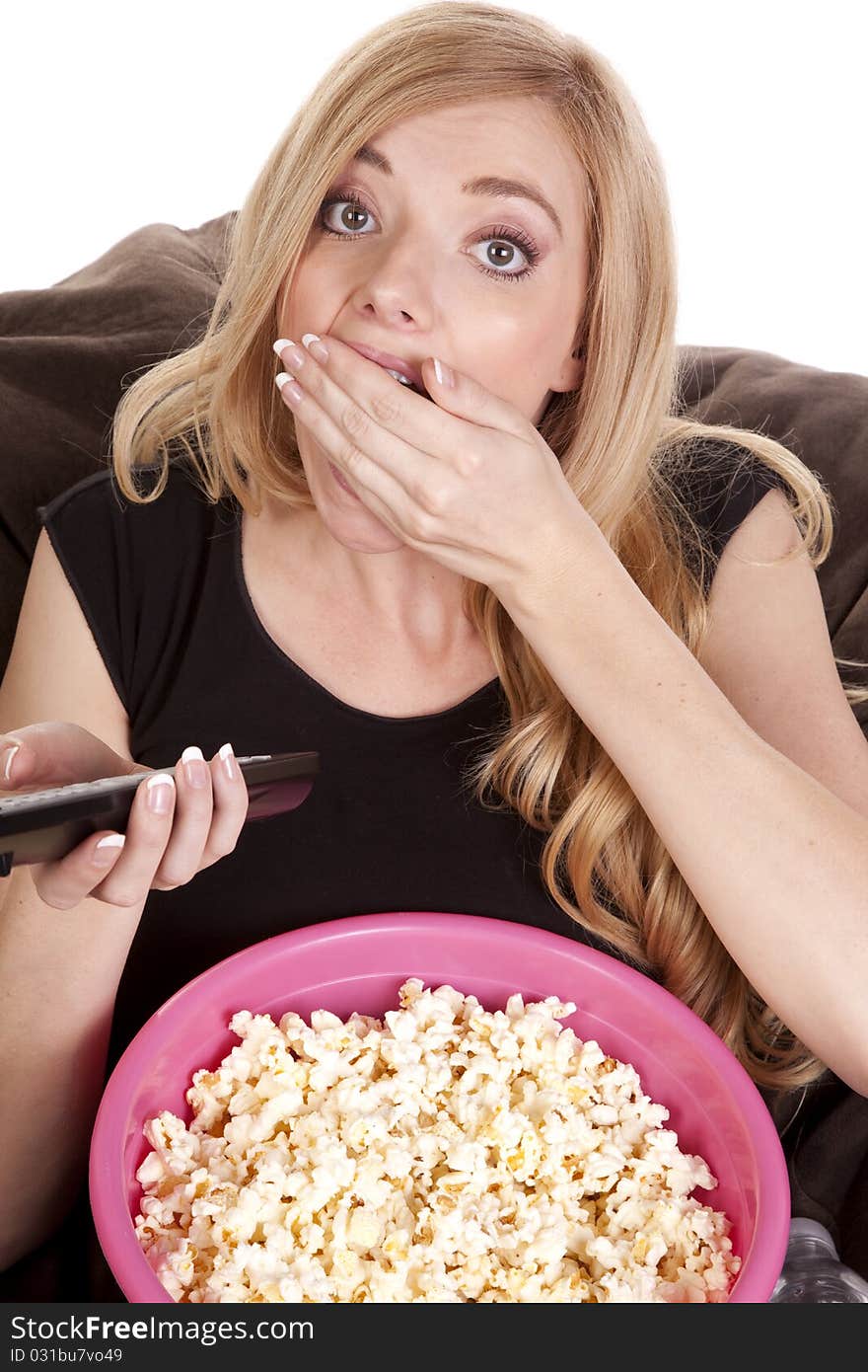 A woman sitting on a bean bag while she is enjoying her popcorn while she is watching tv. A woman sitting on a bean bag while she is enjoying her popcorn while she is watching tv