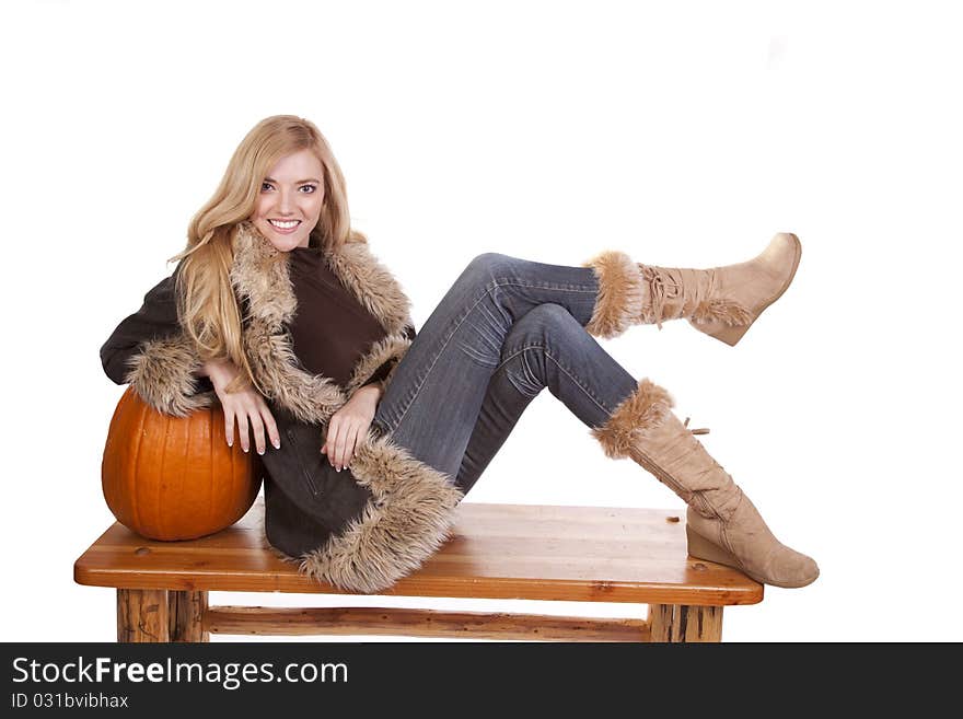 A woman laying on a pumpkin in her warm fuzzy boots and coat. A woman laying on a pumpkin in her warm fuzzy boots and coat.