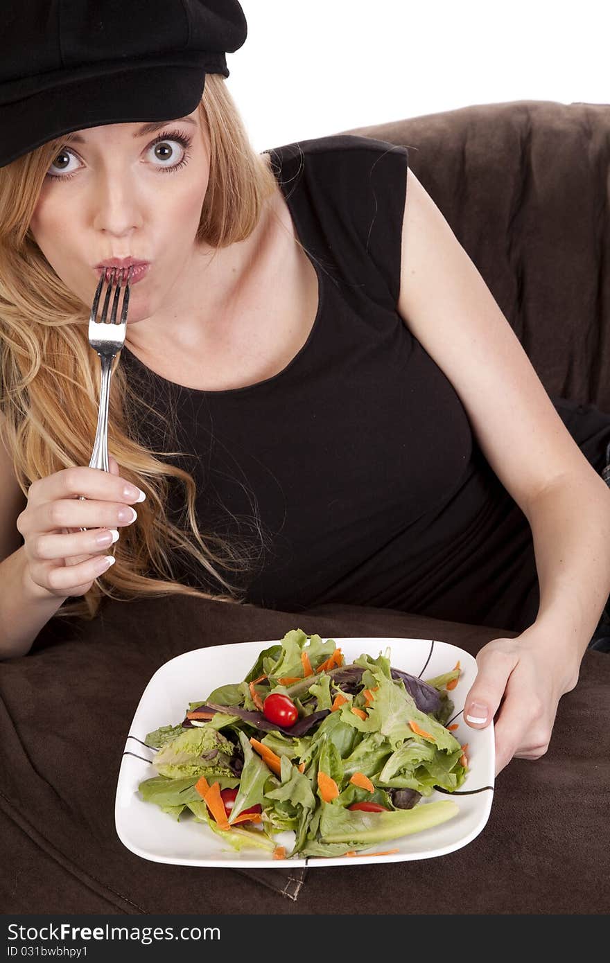 A woman sitting on a bean bag while she is enjoying her nice green salad. A woman sitting on a bean bag while she is enjoying her nice green salad.