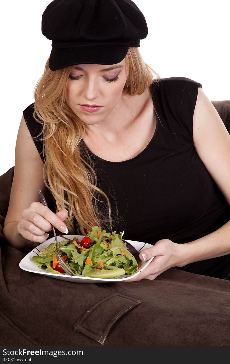 A woman sitting on a bean bag while she is enjoying her nice green salad. A woman sitting on a bean bag while she is enjoying her nice green salad.