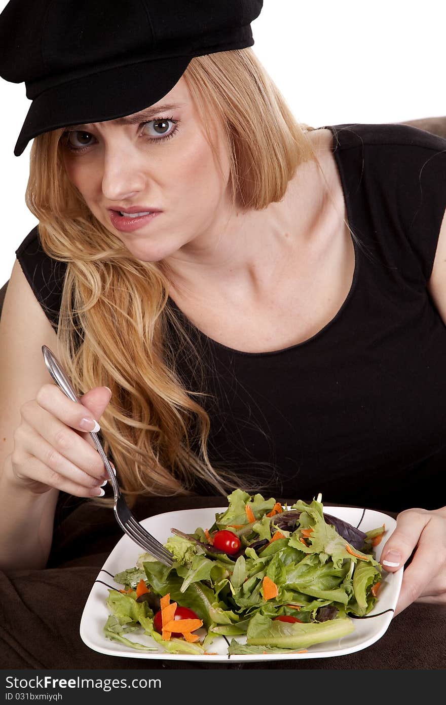 A woman sitting on a bean bag while she is showing a yucky face. She doesn't like her salad. A woman sitting on a bean bag while she is showing a yucky face. She doesn't like her salad.