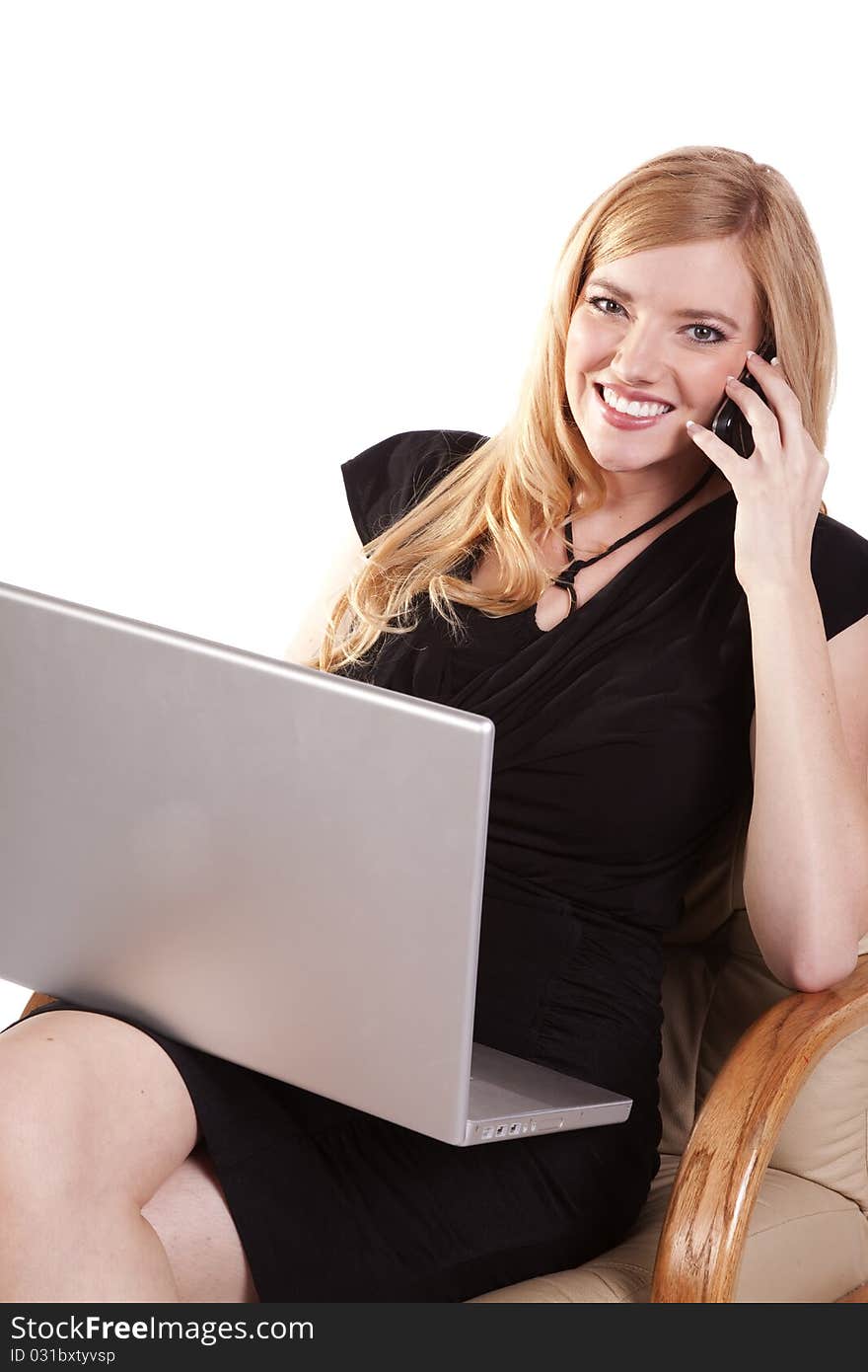 A business woman listening to a call on her cell while she is working on her laptop. A business woman listening to a call on her cell while she is working on her laptop.