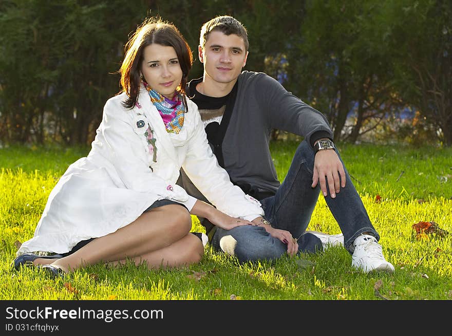 Young couple sitting in the autumn city park (defocused background). Young couple sitting in the autumn city park (defocused background)