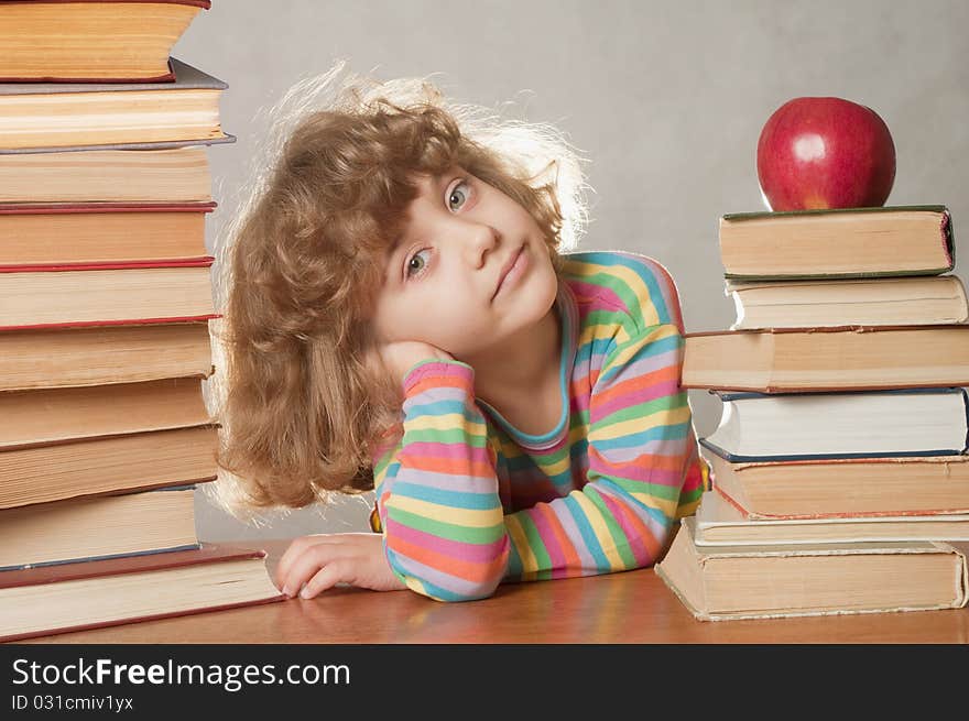 Little girl with pile of books and apple.