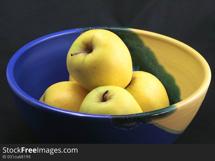 Basket of yellow apples on a black background