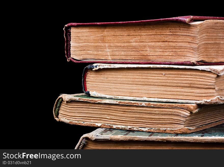 A few old books stacked in a pile on a black background