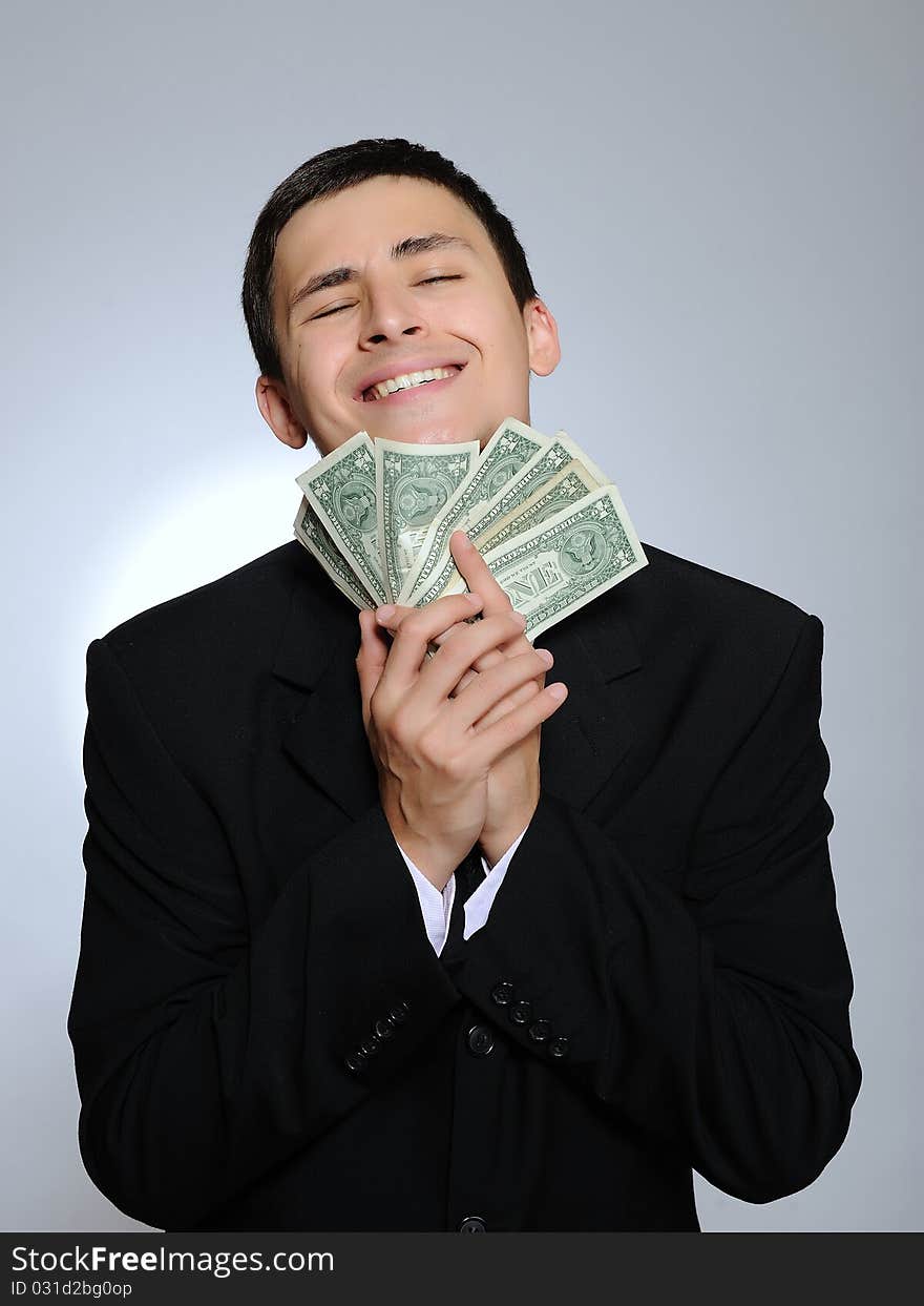 Expressions - Young handsome business man in black suit and tie counting money. gray background. Expressions - Young handsome business man in black suit and tie counting money. gray background