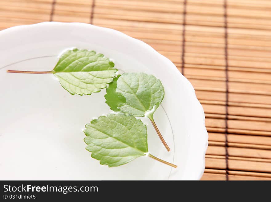 Leaves decorating a white plate on a bamboo sticks table