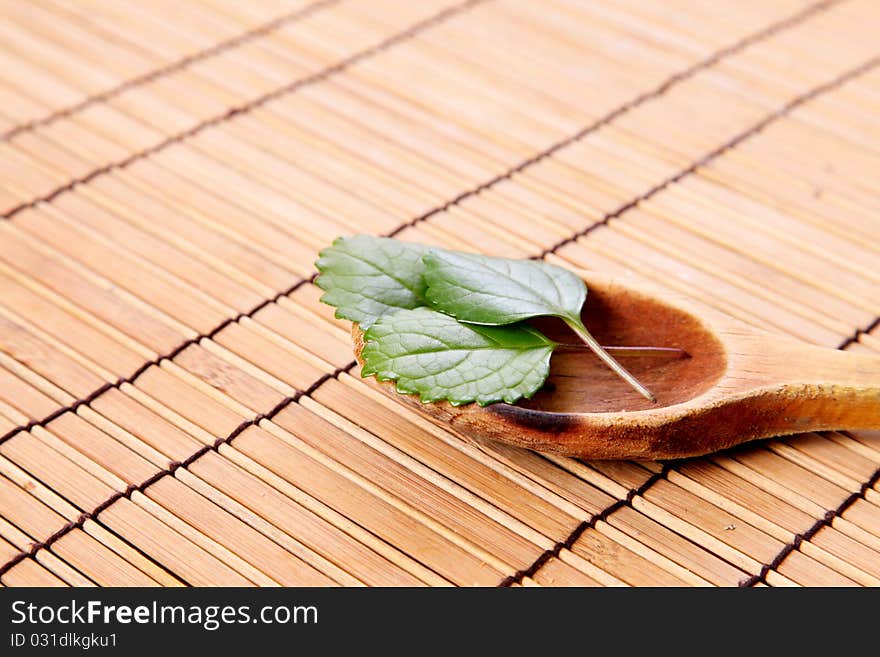 Leaves decorating a wooden spoon on a bamboo sticks table