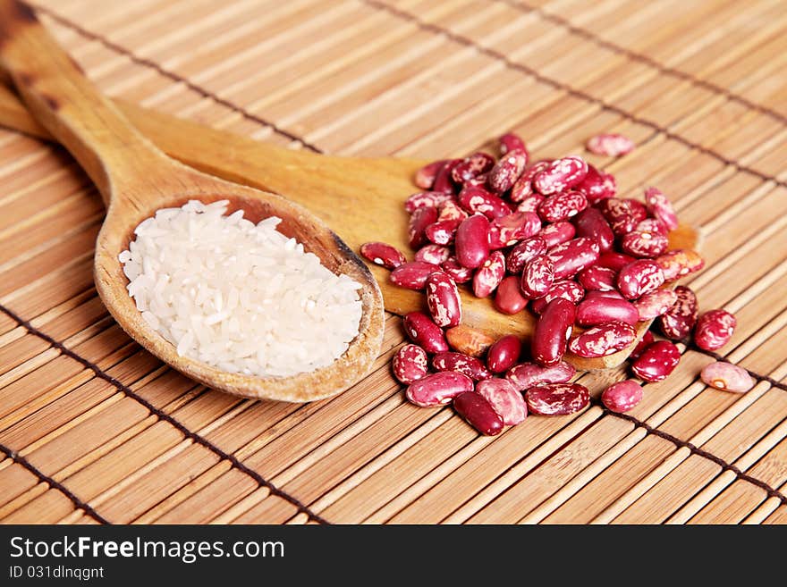 Wooden spoons with beans and rice over bamboo background. Wooden spoons with beans and rice over bamboo background