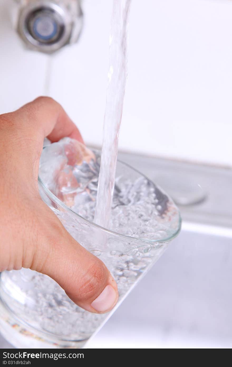 Water pouring into a glass from a faucet. Water pouring into a glass from a faucet