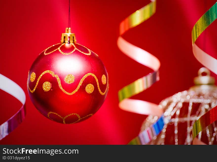 Red christmas ball and golden tinsel hang. Red background