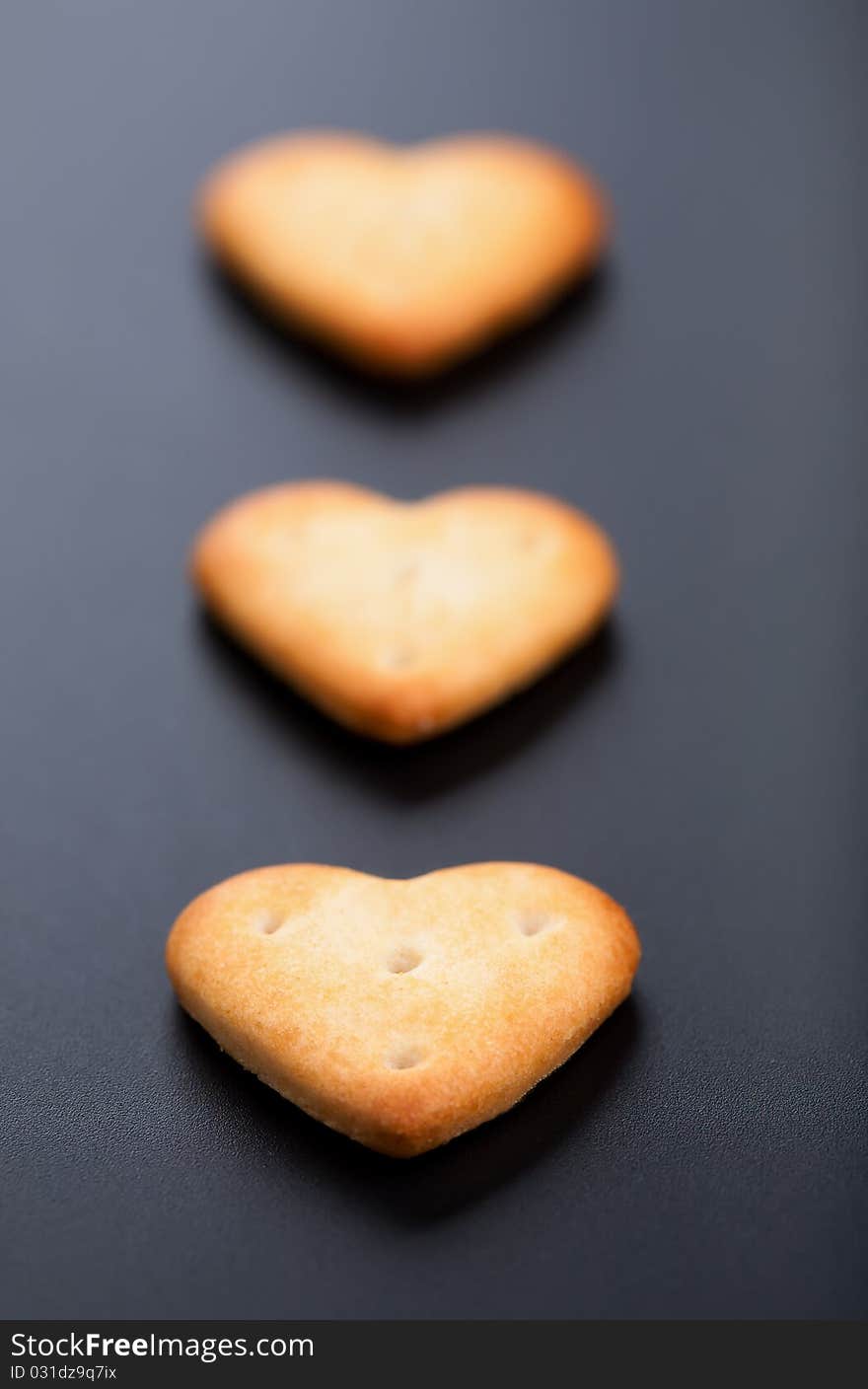 Three salted heart shaped crackers on black background. Three salted heart shaped crackers on black background