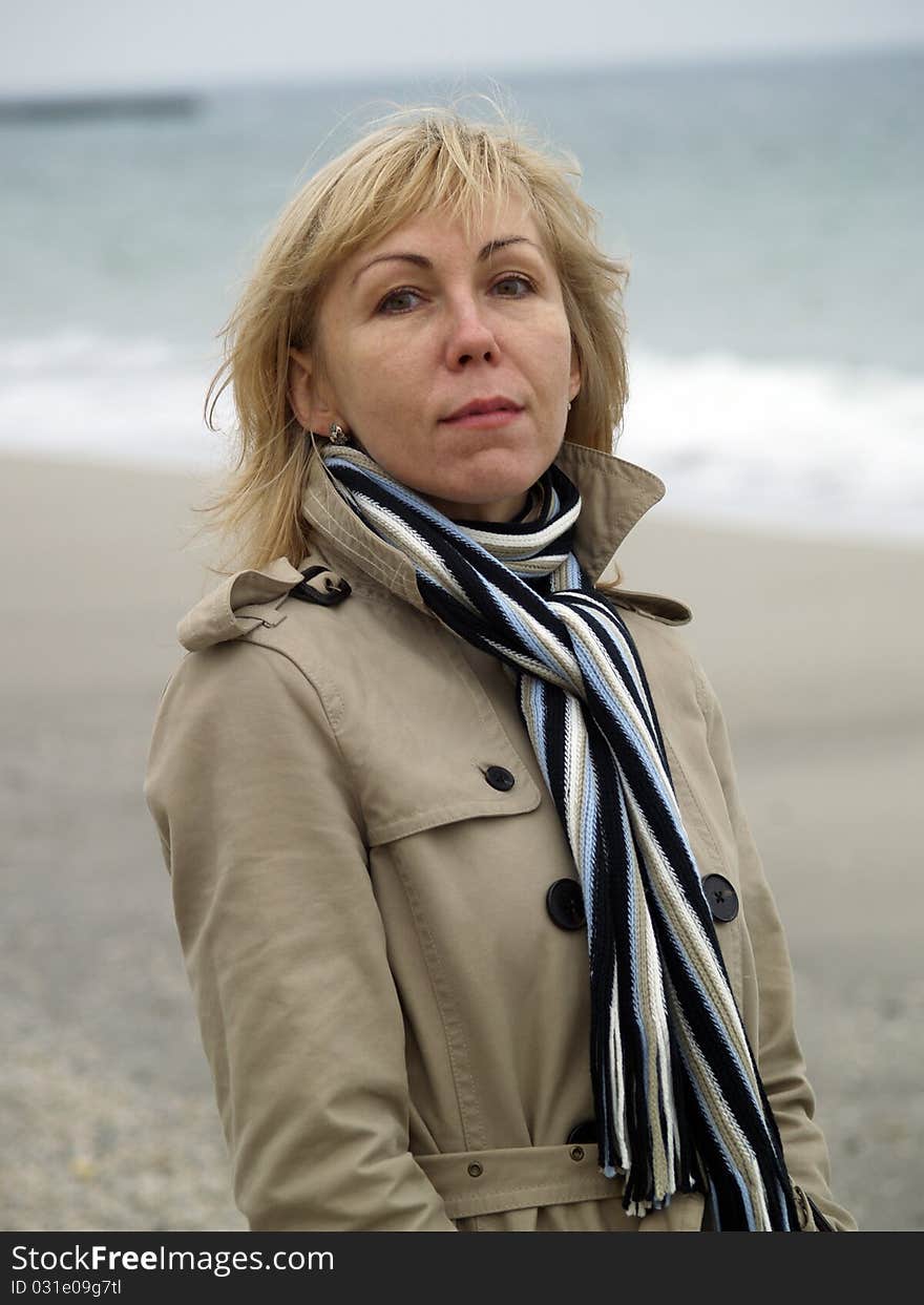 Mid-aged blonde lady staying on sea shore autumn. Mid-aged blonde lady staying on sea shore autumn