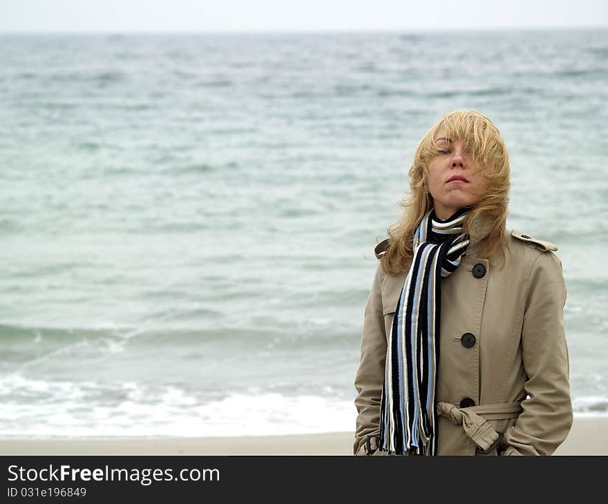 Mid-aged blonde lady staying on sea shore autumn. Mid-aged blonde lady staying on sea shore autumn